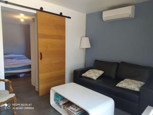 - un salon avec un canapé noir et un lit dans l'établissement La cigalière, au Beausset