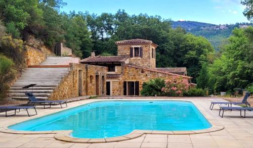 - une piscine en face d'une maison en pierre dans l'établissement Magnifique Mas avec Piscine - La Bergerie du Razès, à Alet-les-Bains