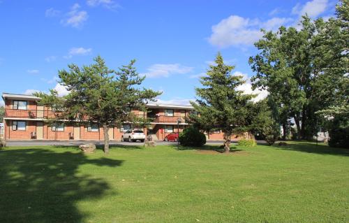 a building with trees in front of a yard at Motel Du Fleuve in Brossard