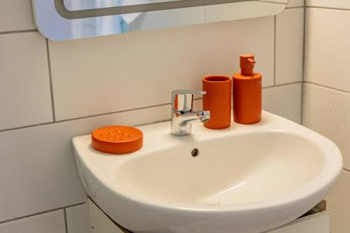 a bathroom sink with two orange containers on it at Bungalow Rubis in Le Gosier