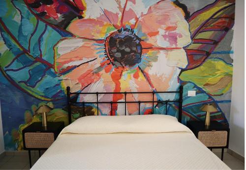 a bedroom with a painting of flowers on the wall at L'AQUILA Apartment in LʼAquila