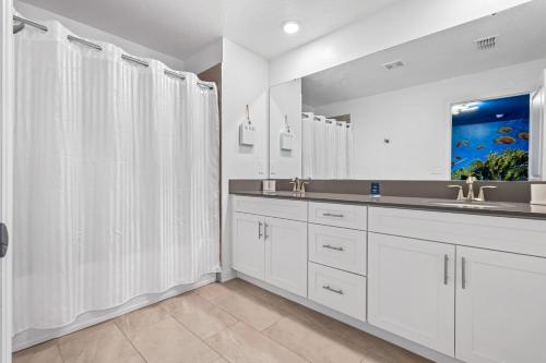 een witte badkamer met een wastafel en een spiegel bij 4327 Create Memories in a Magical 5BD Home in Kissimmee