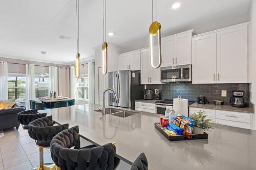 a large kitchen with white cabinets and a table and chairs at 4327 Create Memories in a Magical 5BD Home in Kissimmee