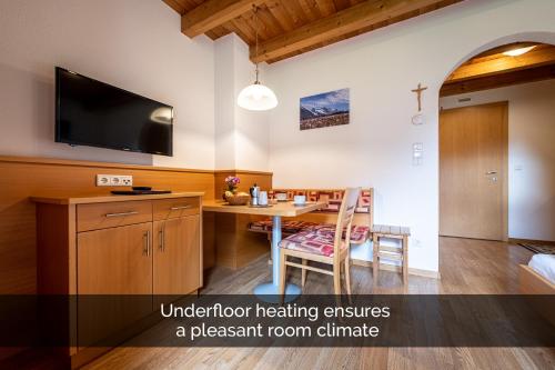 an apartment kitchen with a dining table and a flat screen tv at Apartments Nature Apis Landheim in Anterselva di Mezzo