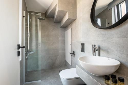 Un baño con lavabo, inodoro y espejo. en Amarillide rooms, en La Canea