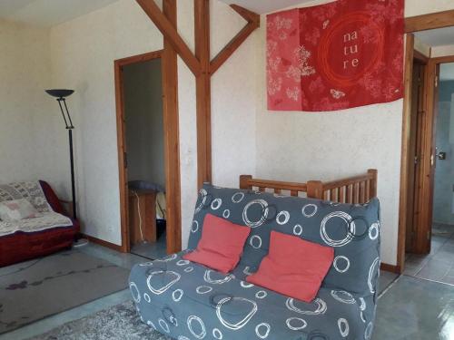 - un salon avec un canapé et 2 oreillers rouges dans l'établissement Chalet 3 chambres point de vue depuis la grande terrasse, à Sainte-Colombe