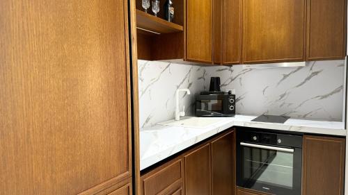 a kitchen with wooden cabinets and a black microwave at Anchor Luxury Rooms in Vlorë