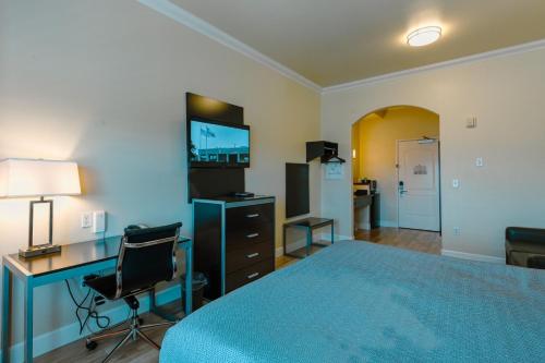 a bedroom with a bed and a desk and a television at Gateway Inn and Suites San Francisco SFO Airport in San Bruno