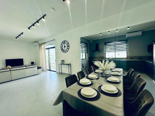 a dining room with a table and chairs and a clock at New, modern and spacious 4BR apartment in Mellieha in Mellieħa