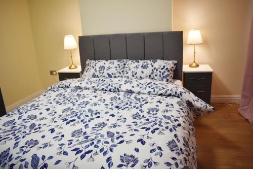a bed with a blue and white comforter and two lamps at Birmingham City Centre Bedroom, Parking, WiFi, Kitchen, Living room in Birmingham