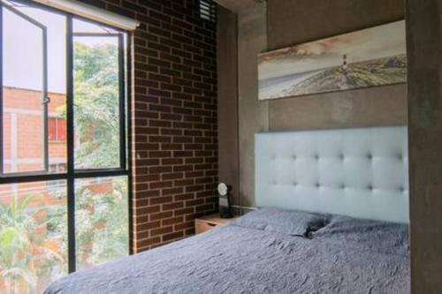 a bedroom with a bed and a brick wall at Acogedor y Central Apartaestudio en Envigado -C3 in Envigado