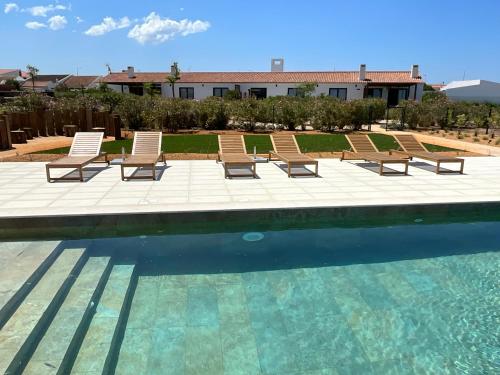 a group of chairs sitting next to a swimming pool at Quinta do Planalto Vicentino - Casas de Campo in Aljezur