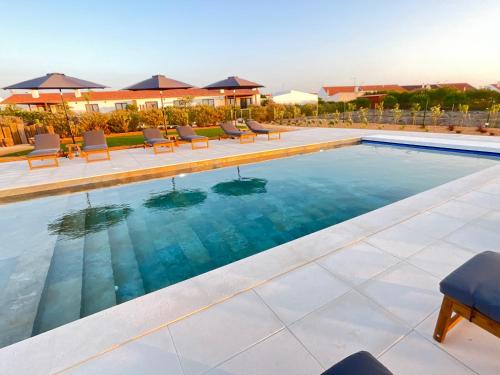 a large swimming pool with chairs and tables at Quinta do Planalto Vicentino - Casas de Campo in Aljezur