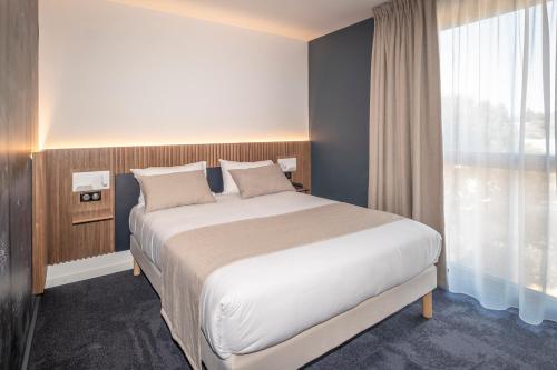 a bedroom with a large bed and a large window at Hôtel Le Relais des Brasseurs - Aubagne in Aubagne