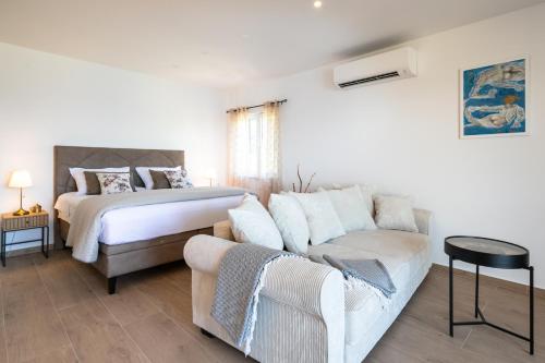 a white bedroom with a bed and a couch at Apartmani Doro in Vela Luka