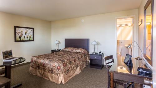 a hotel room with a bed and a desk at Motel Du Fleuve in Brossard