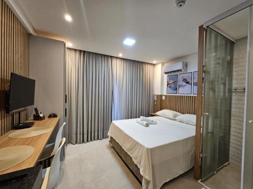 a bedroom with a bed and a desk and a computer at Get By Side - Jardim Oceania in Tambaú