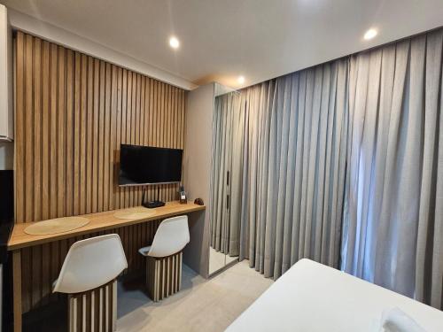 a hotel room with a desk and a television at Get By Side - Jardim Oceania in Tambaú