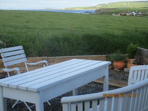 a white table and two chairs and a view of the ocean at Little Nook, Dunseverick in Dunseverick