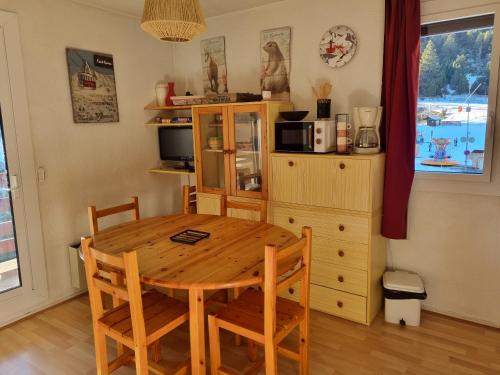 - une cuisine avec une table en bois, des chaises et un four micro-ondes dans l'établissement Appart au pied des pistes - P2000, à Bolquère-Pyrénées 2000