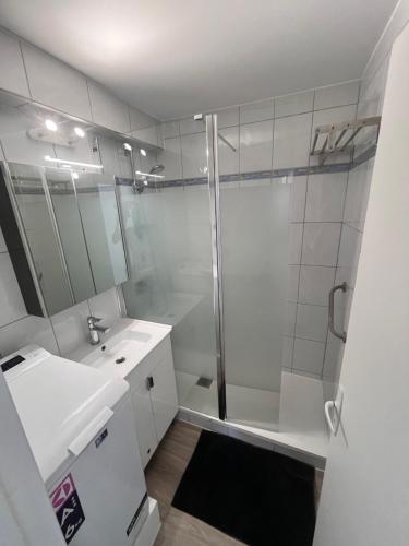 une salle de bain blanche avec une douche et un lavabo dans l'établissement L'appart D79, à Gruissan
