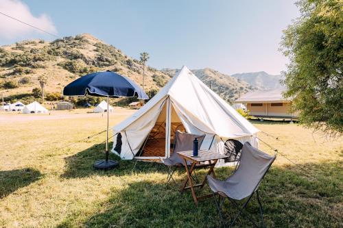 a tent with a table and chairs in a field at White’s Landing Catalina Camp in Avalon