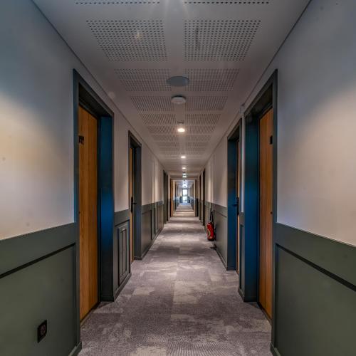 an empty hallway in an office building with blue doors at Hôtel Le Relais des Brasseurs - Aubagne in Aubagne