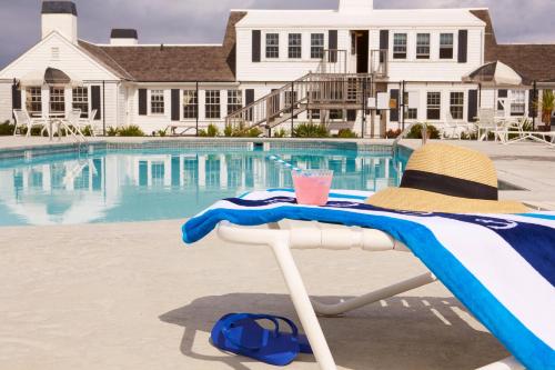 a beach chair with a drink on it next to a pool at Kalmar Village & Tradewinds in North Truro