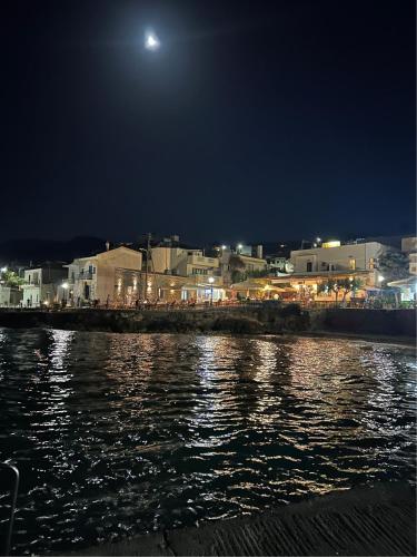 a city at night with the moon over the water at Mandora's Sea view apartment in Mochlos