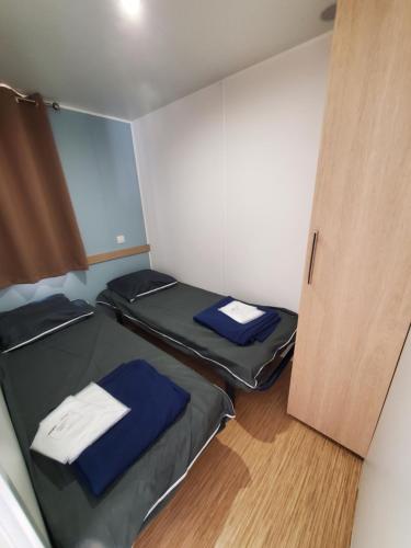 Cette petite chambre comprend 2 lits et une porte. dans l'établissement Mobilhome La Marine, au Grau-du-Roi