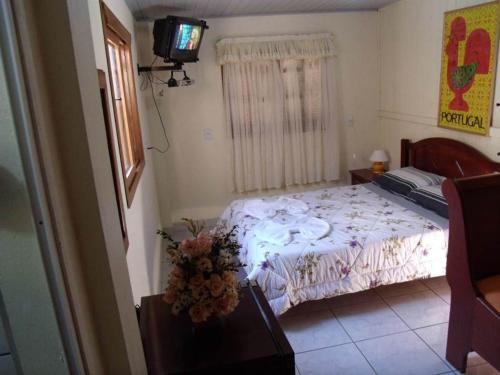 1 dormitorio con 1 cama y TV en Pousada da Mari, en Gramado