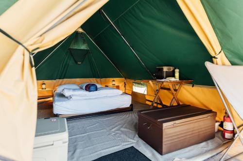 a green and yellow tent with a bed and a desk at White’s Landing Catalina Camp in Avalon