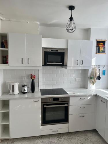 une cuisine avec des armoires blanches et un four à plaques de cuisson dans l'établissement Appartement proche La Villette avec 2 balcons, à Pantin