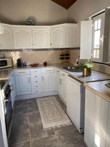 a white kitchen with white cabinets and a sink at Casa da Avó Ana - Montargil in Montargil