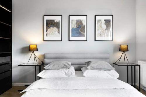 Biała sypialnia z czterema obrazami na ścianie w obiekcie Blue Raven Downtown Apartments w Gdańsku