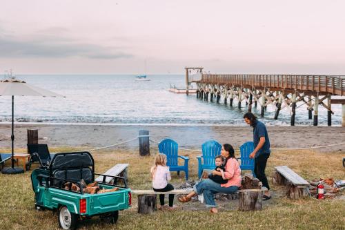 a group of people sitting on a bench at the beach at White’s Landing Catalina Camp in Avalon