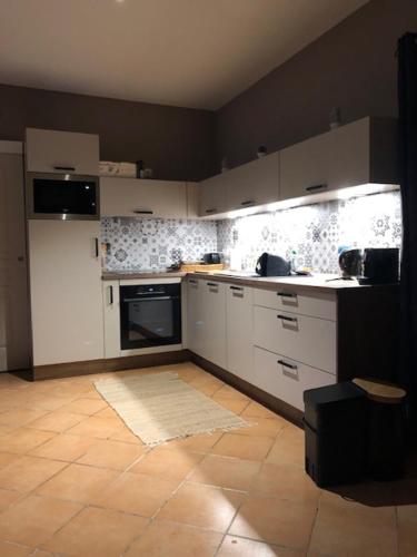 une cuisine avec des armoires blanches et un sol carrelé dans l'établissement Le refuge, à Lesparre-Médoc