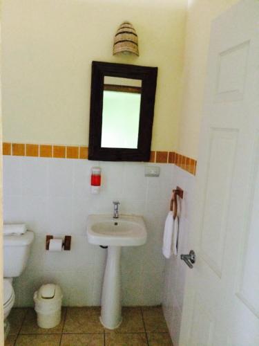 a bathroom with a sink and a mirror and a toilet at Hotel Bahia Taitza in Flores
