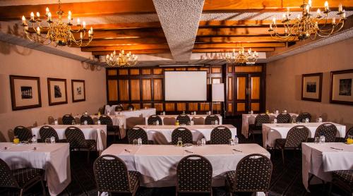 a banquet room with white tables and chairs and a screen at The Royal Hotel by Coastlands Hotels & Resorts in Durban