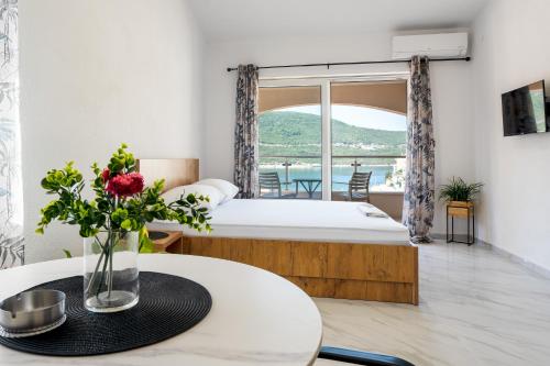 a bedroom with a bed and a table with a vase of flowers at Apartmani Divna in Neum