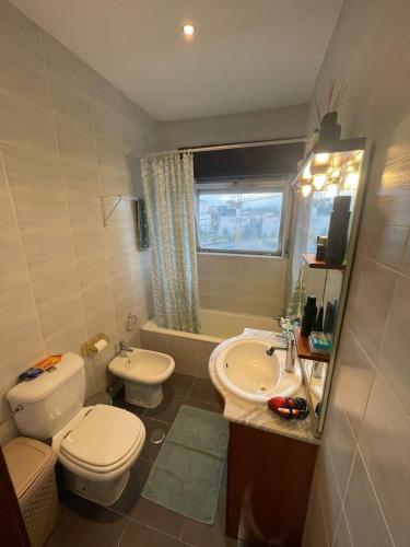 a bathroom with a toilet and a sink and a tub at Flor da Providência in Viseu