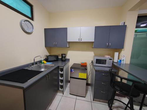 a small kitchen with a sink and a microwave at Hotel Bamboo Aeropuerto in Alajuela City