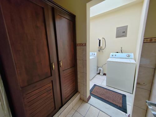 a bathroom with a door and a washer and dryer at Hotel Bamboo Aeropuerto in Alajuela City