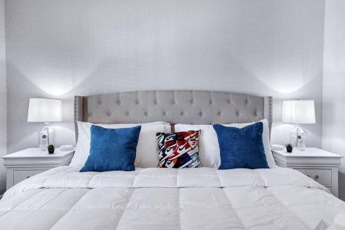 a white bed with blue pillows and two white night stands at The shoe LA-LA house in San Antonio