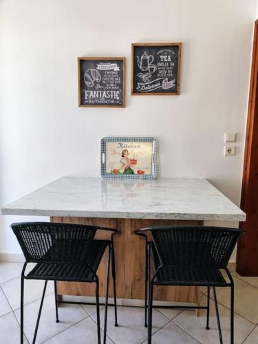 a table with two chairs and a counter with two pictures at Filip and Myrsinis house - apartment in Ayios Nikolaos Sithonia