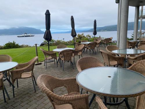 a patio with tables and chairs and a view of the water at Smaken av Ryfylke Event AS overnatting, Bygningen drives ikke som hotell in Hjelmeland