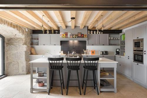 une cuisine avec des placards blancs et un îlot avec des tabourets de bar dans l'établissement Grande maison de famille, au Chambon-sur-Lignon