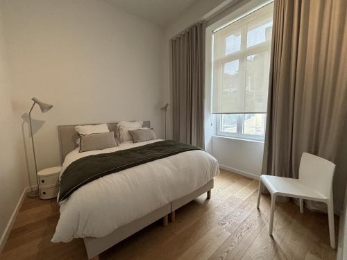 une chambre avec un lit, une fenêtre et une chaise dans l'établissement Brehat T3, sea view, à Trébeurden