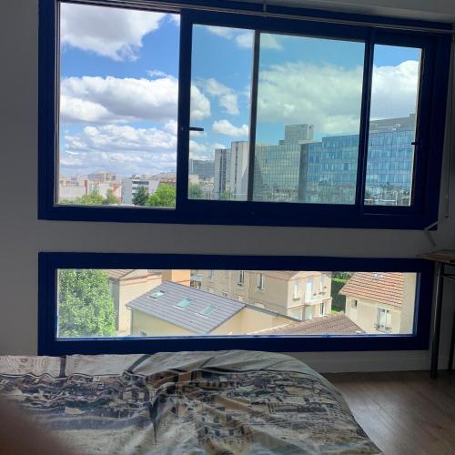 a bedroom with a view of a city from a window at Paris La Défense - Santorin Apartment with jacuzzi in Courbevoie
