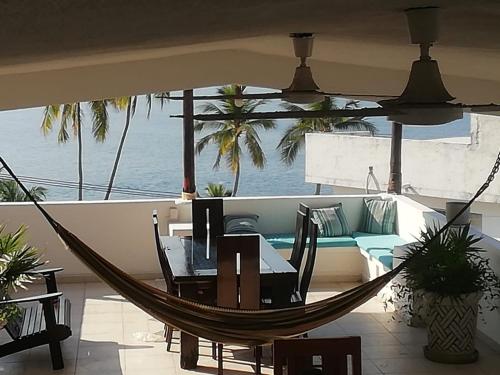 a hammock on a balcony with a table and a couch at Casa Las iguanas in Acapulco